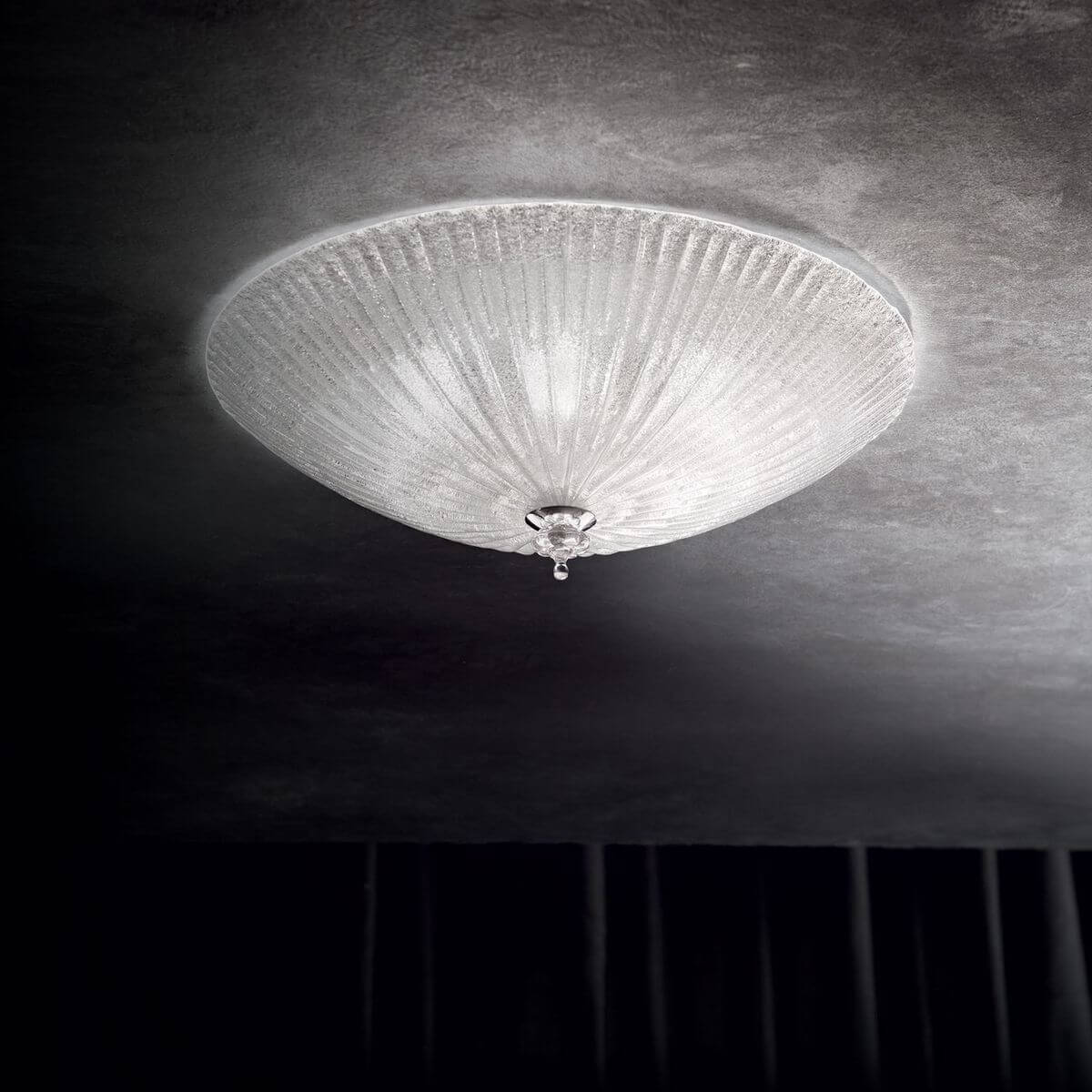 Plafonnier allumé au plafond dans une pièce sombre, lumière diffuse