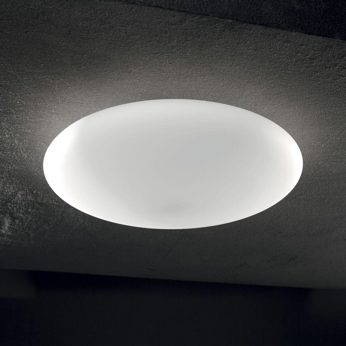 Luminaire allumé au plafond sombre diffusant un halo de lumière blanche uniforme