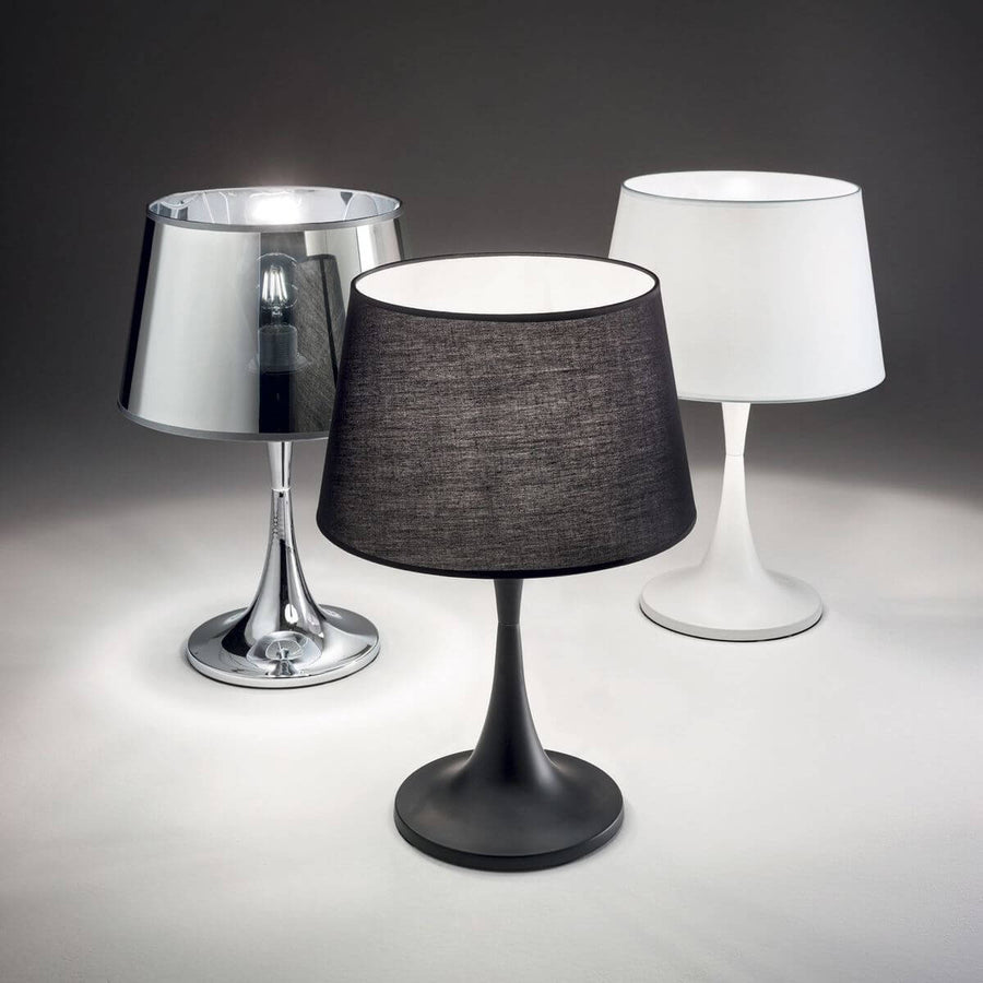 Trois lampes identiques posées côte à côte en finitions chromée, noire chinée et blanche