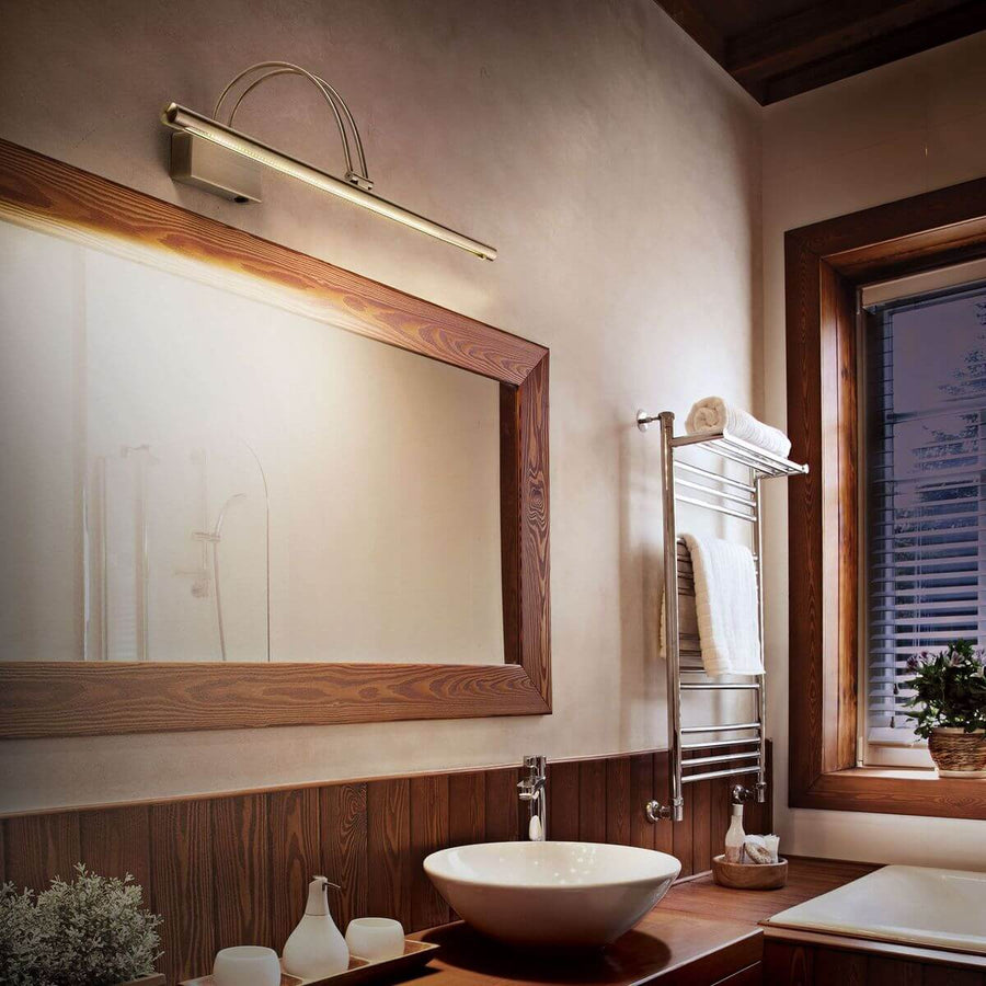 Applique murale dorée installée au-dessus d'un miroir en bois dans une salle de bain.