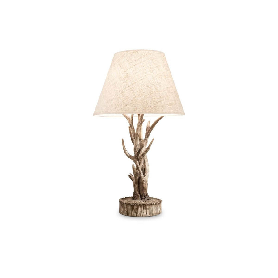 Lampe à poser vue de face sur fond blanc, abat-jour beige et pied en branches sculptées