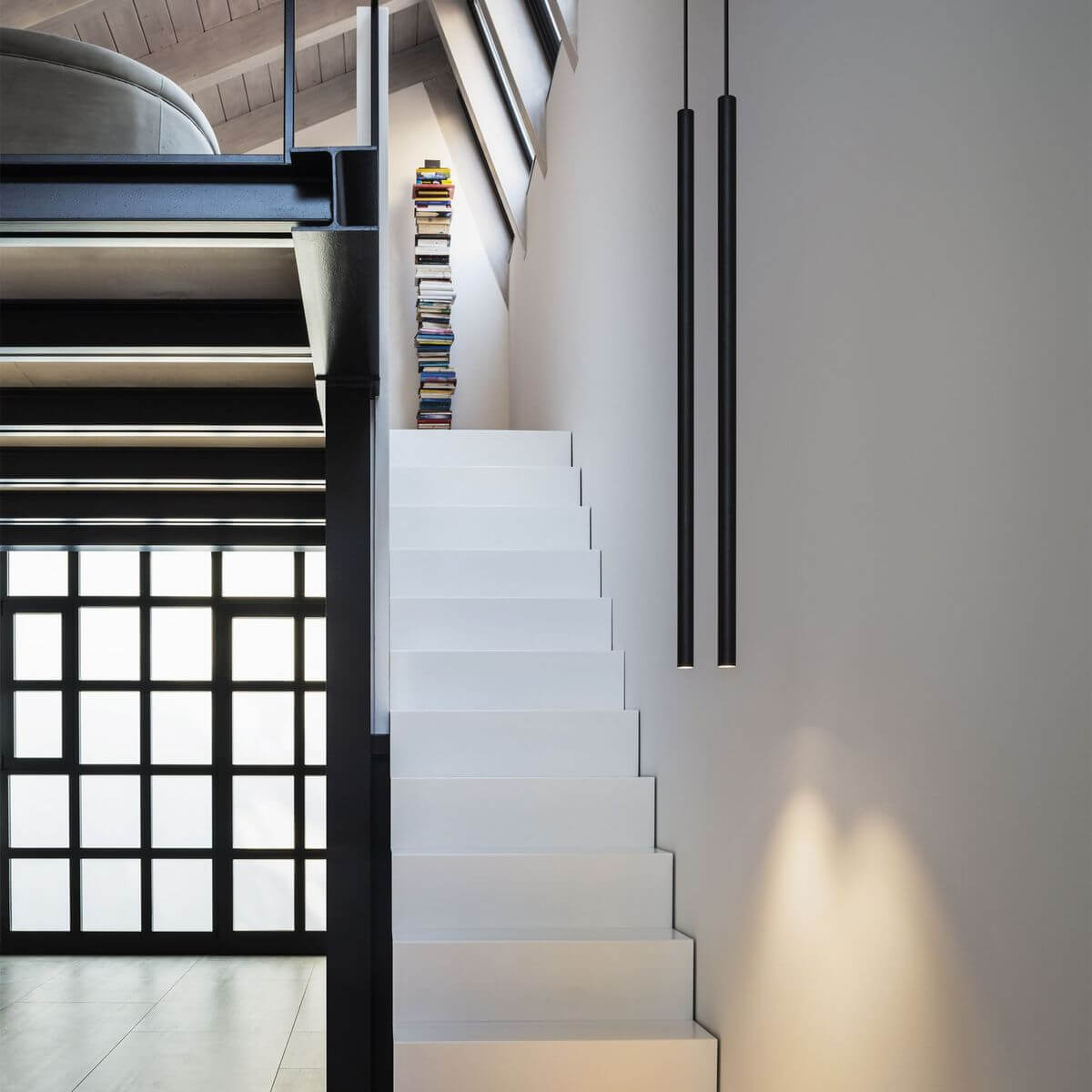 Deux suspensions cylindriques noires devant un escalier blanc, mise en ambiance