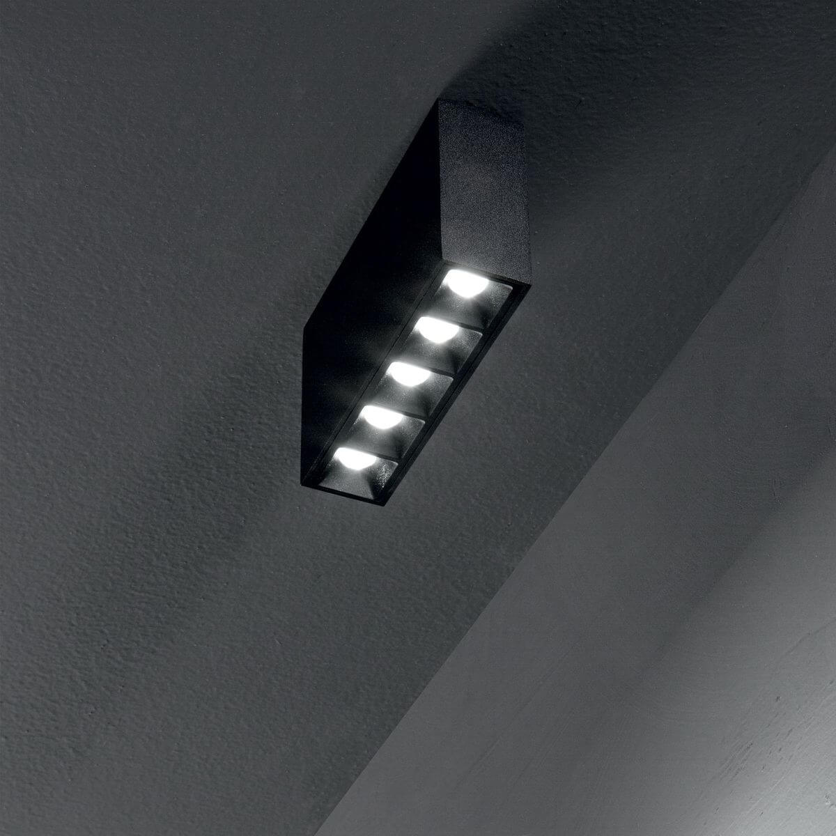 Plafonnier noir installé au plafond, cinq LED allumées en situation sombre