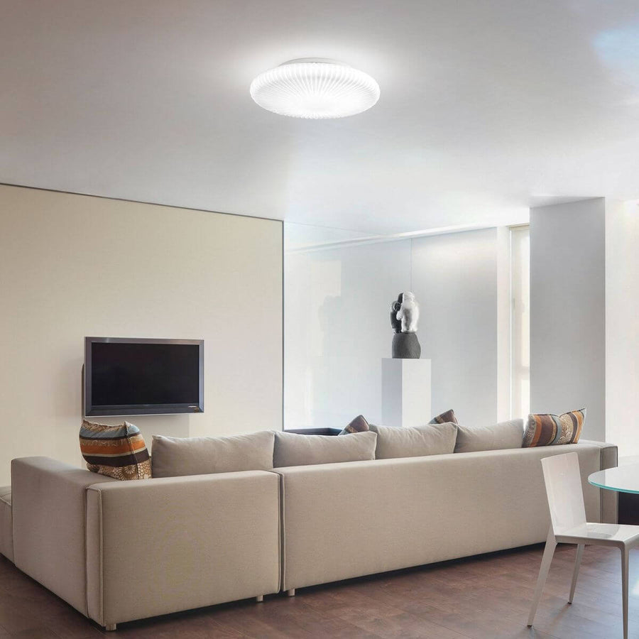 Plafonnier allumé au plafond d'un salon contemporain avec canapé beige