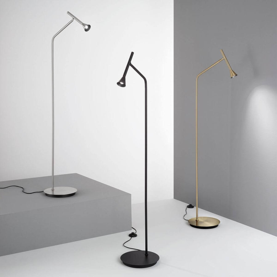 Trois lampadaires nickel, noir et laiton disposés dans un décor gris minimaliste