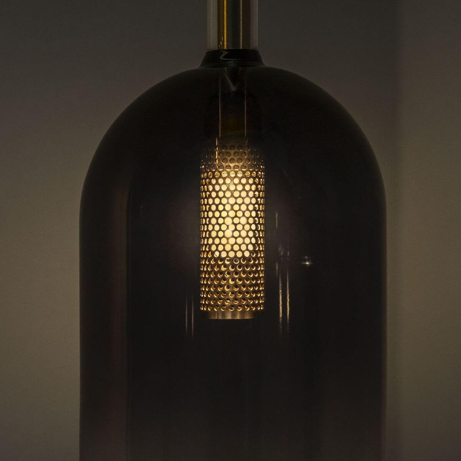 Détail du diffuseur doré perforé éclairé à l'intérieur du verre fumé sombre