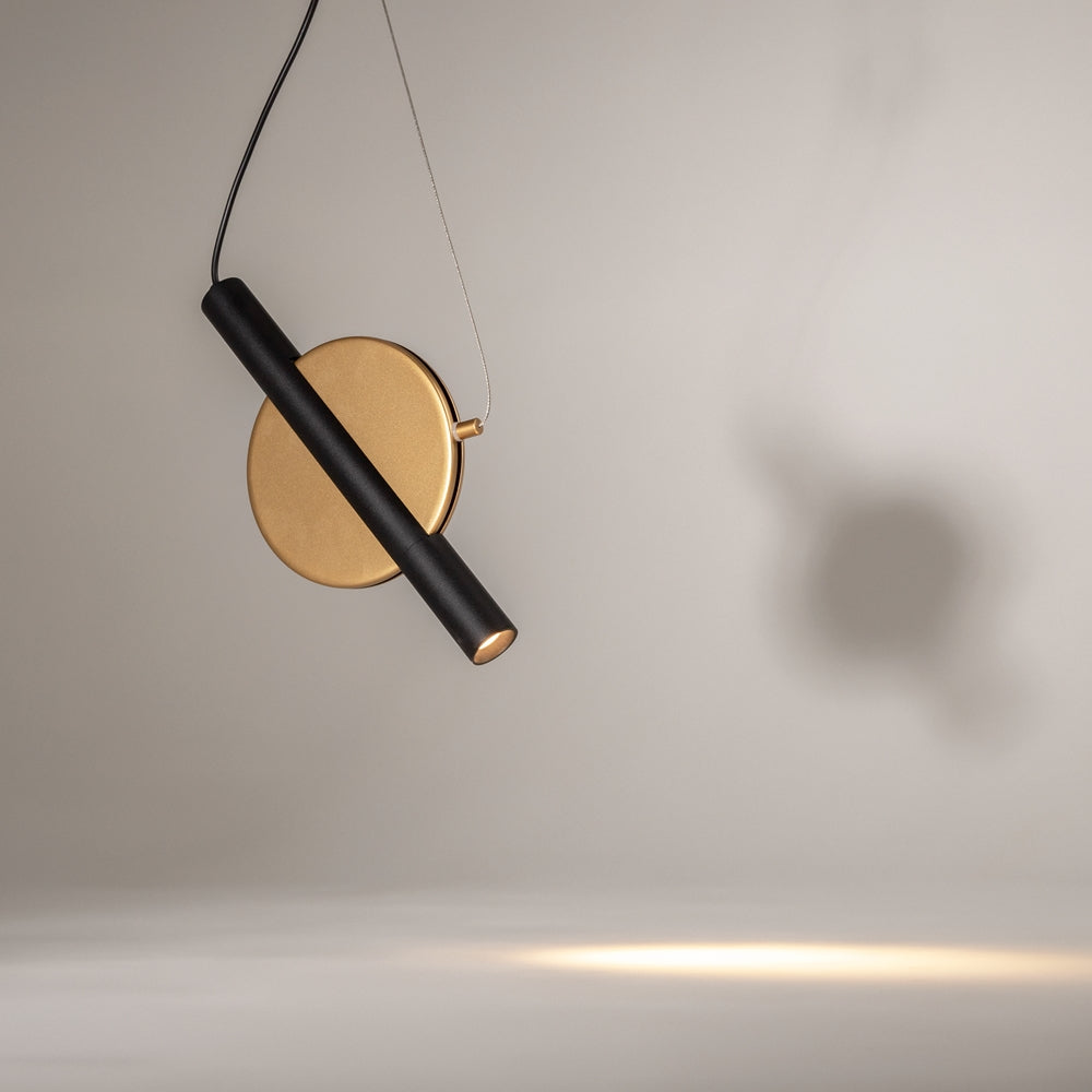 Vue rapprochée du disque doré et du tube noir incliné, ombre portée