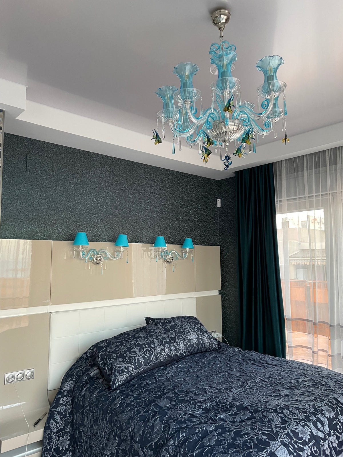 Lustre turquoise fixé au plafond d'une chambre, au-dessus du lit
