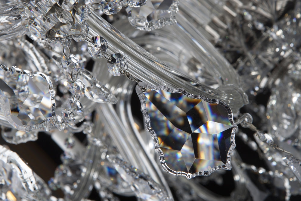 Gros plan sur une pendeloque facettée aux reflets irisés accrochée à une chaînette.