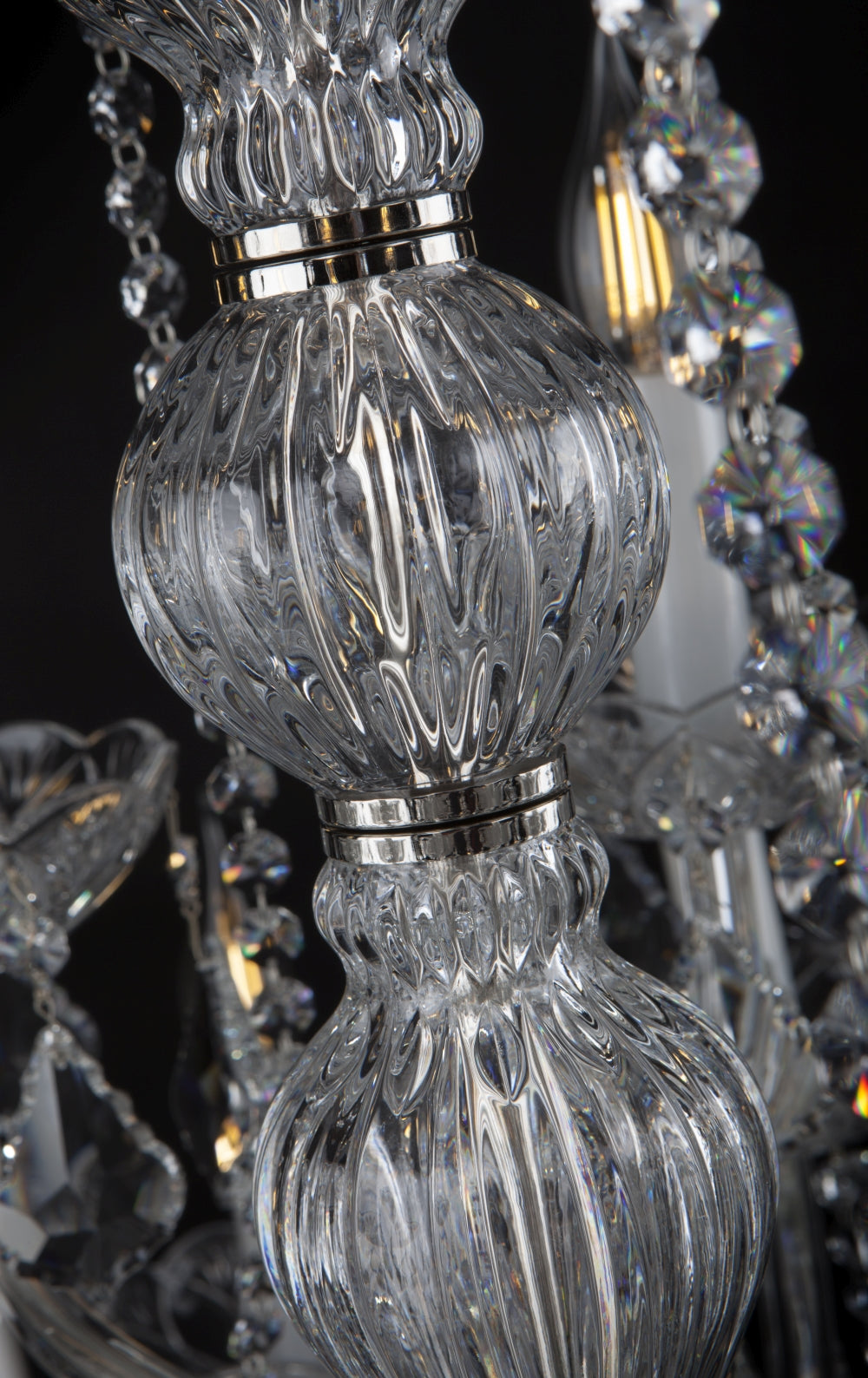 Détail de la colonne centrale en cristal côtelé avec ses bagues métalliques brillantes.