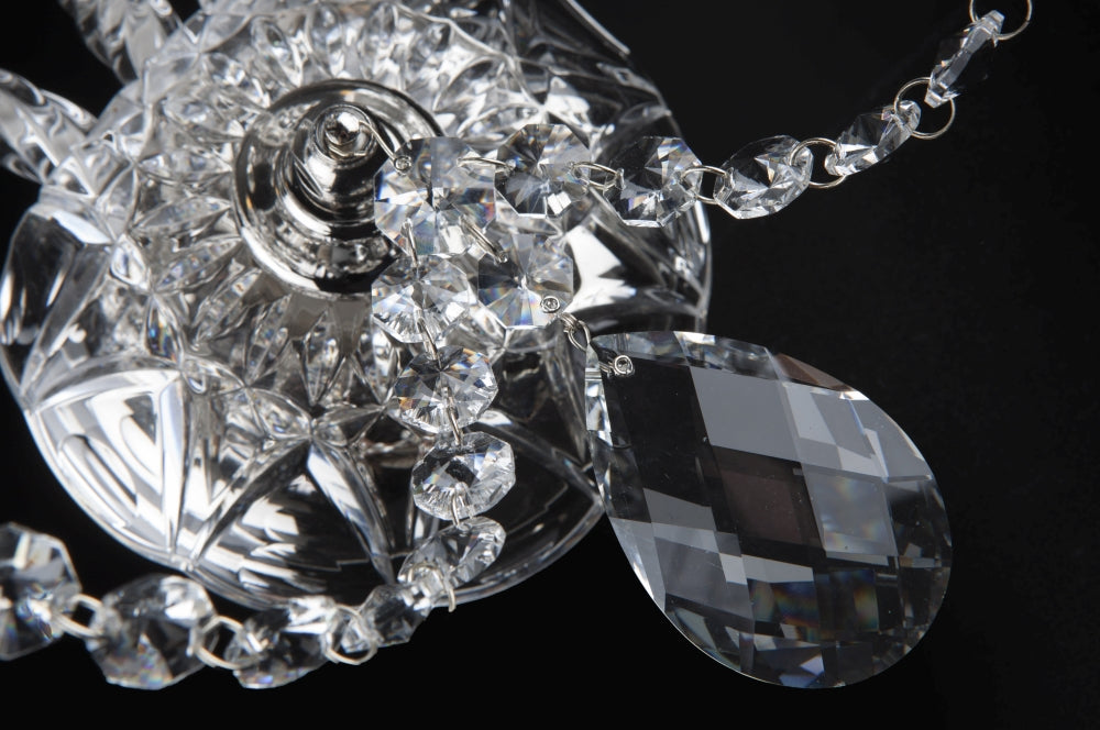 Gros plan sur un pendentif de cristal taillé et la chaînette perlée de l'applique