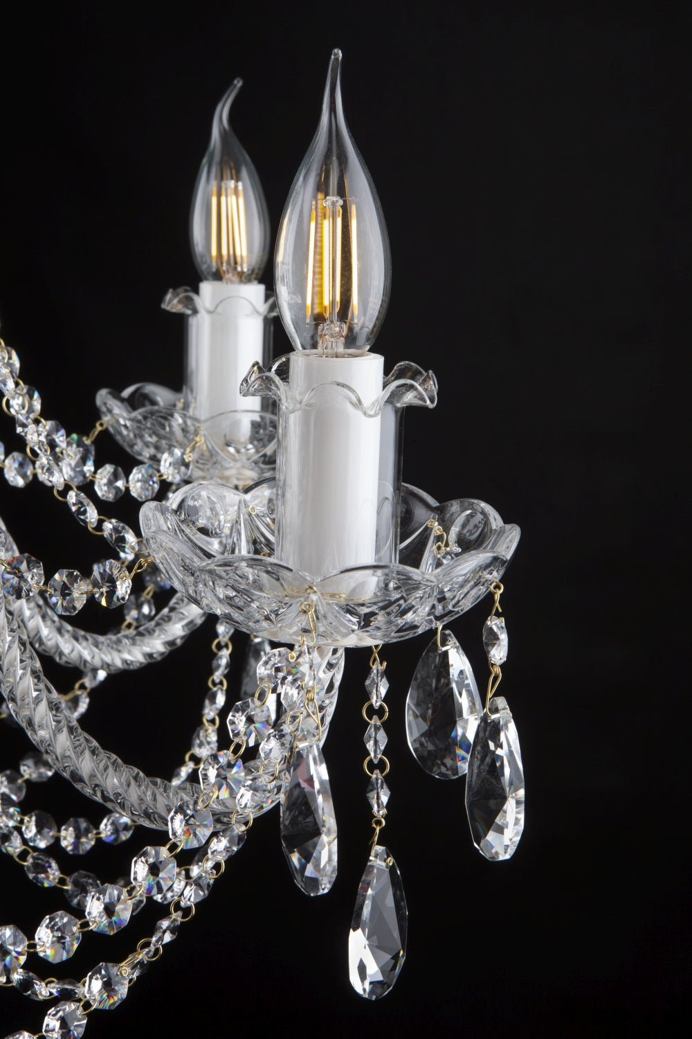 Détail d'une bobèche en cristal, douille blanche et pampilles transparentes.