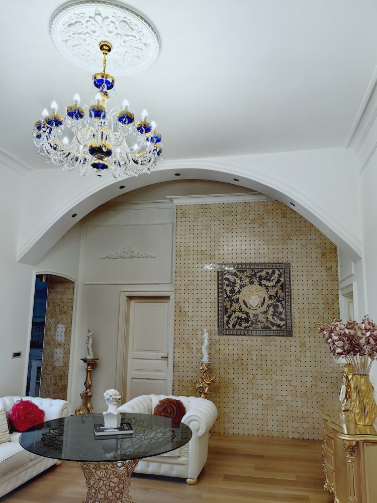 Lustre suspendu sous une rosace de plafond, dans un intérieur blanc avec arche et décor doré.