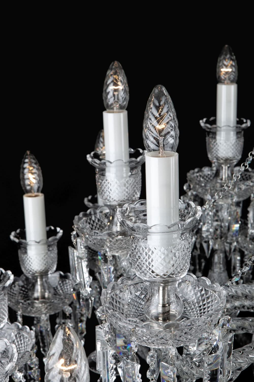 Détail des bras du lustre, bougies blanches et coupes de cristal taillé.