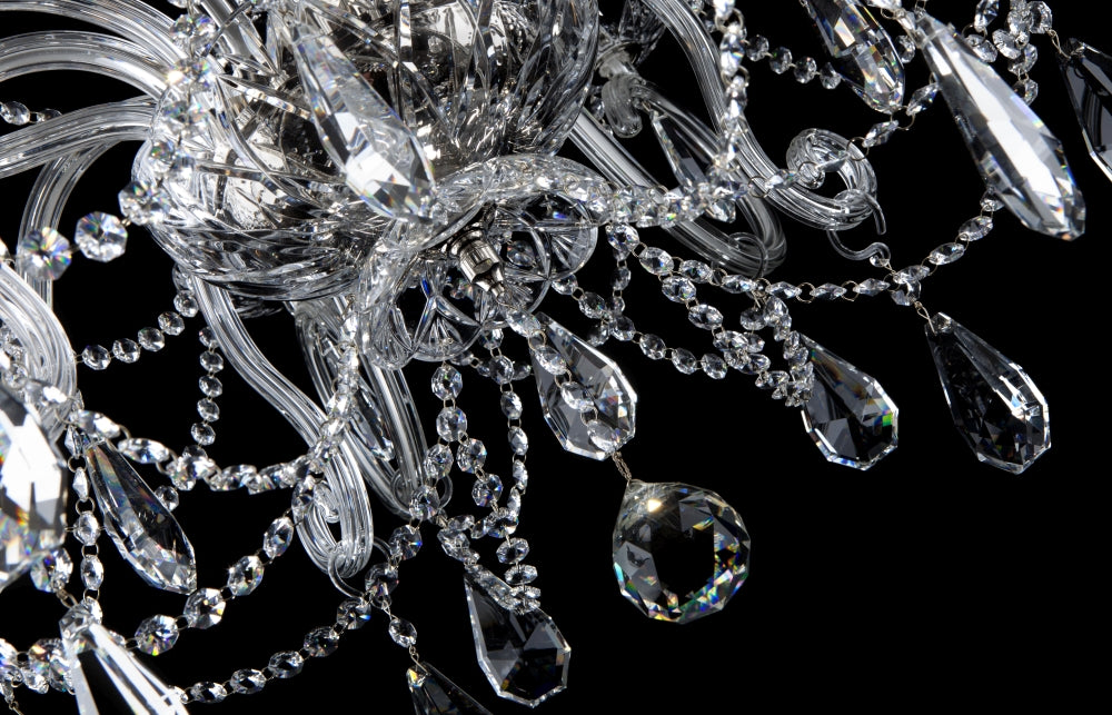 Gros plan du dessous : chaînettes de cristal, bras courbes et gouttes facettées.