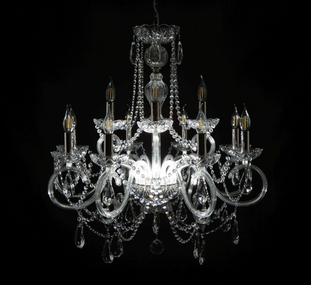 Lustre allumé de face, ampoules visibles, fond noir, cristal étincelant.