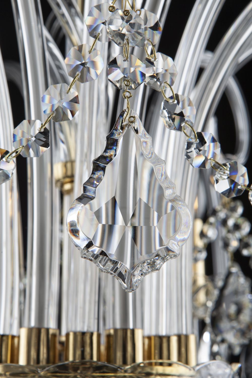 Gros plan sur une pendeloque de cristal taillé suspendue entre les tiges de verre