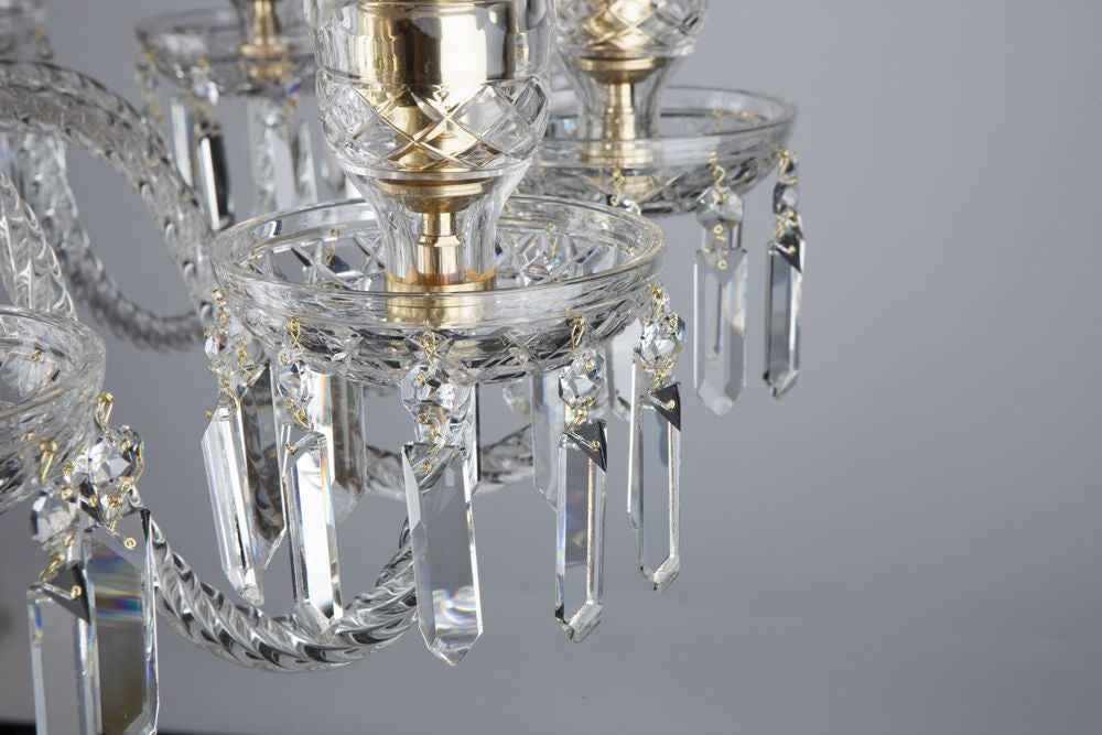 Détail des bras recourbés, pampilles en cristal taillé et coupelles dorées du lustre.