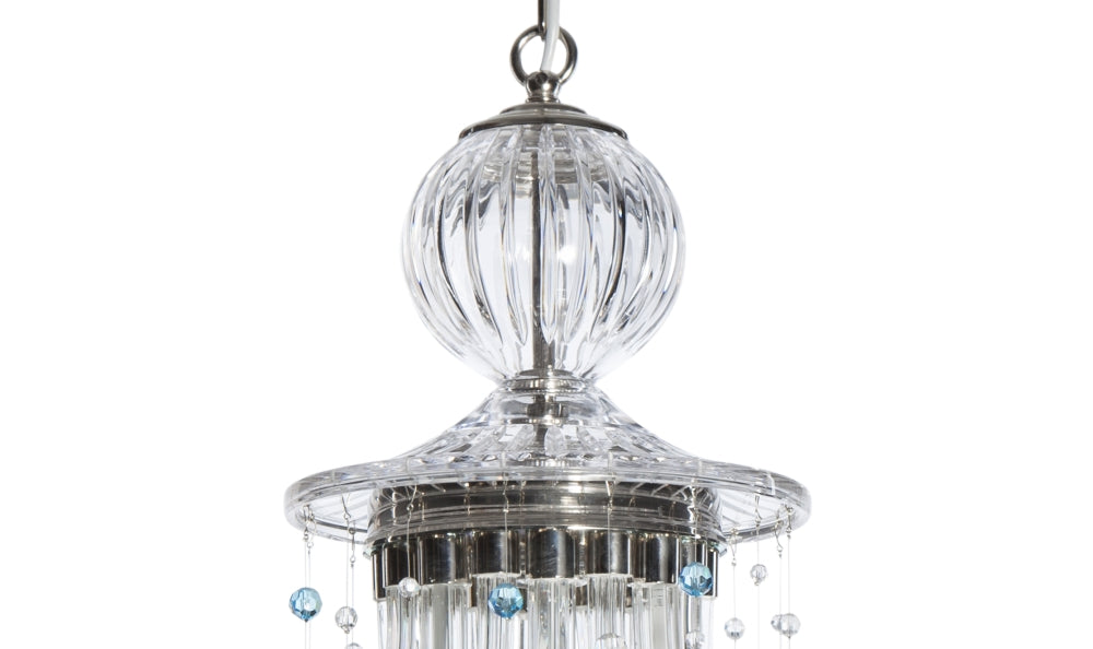 Détail du sommet : boule en verre strié, collerette métallique et chaînettes de perles.
