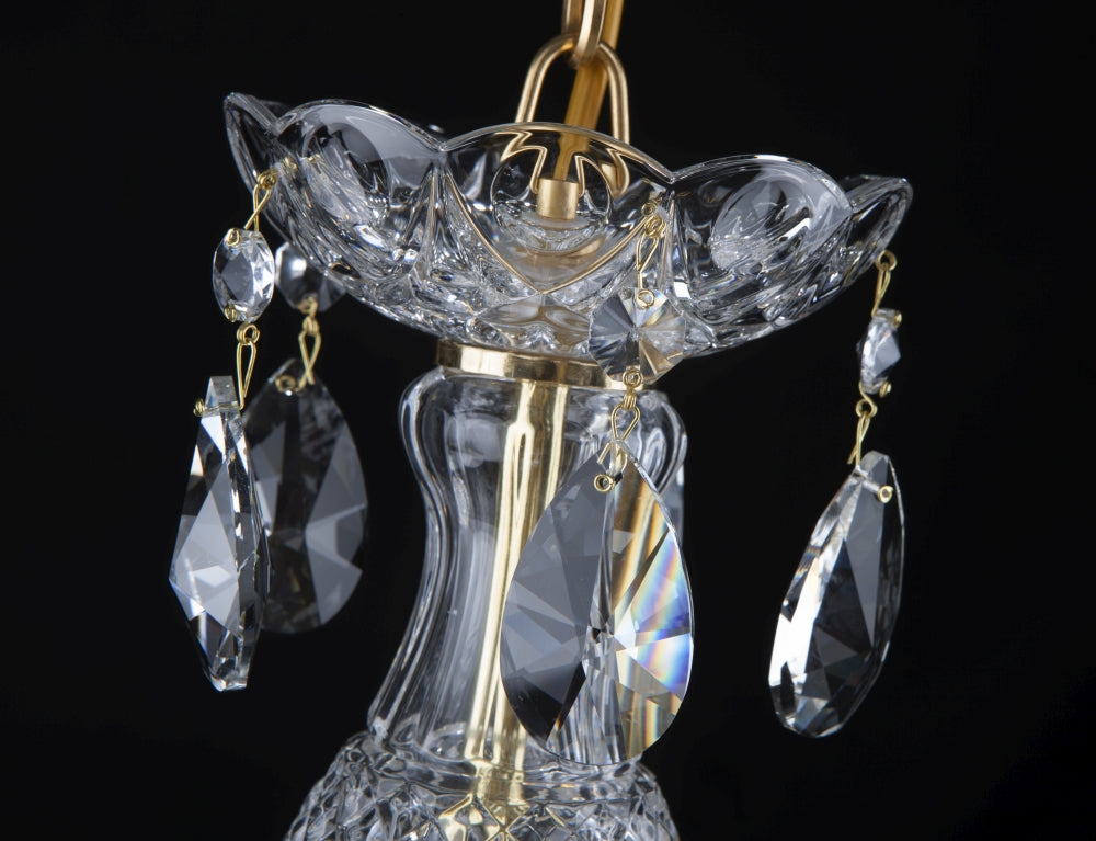 Gros plan sur la coupole supérieure, tige dorée et pendants losange en cristal.