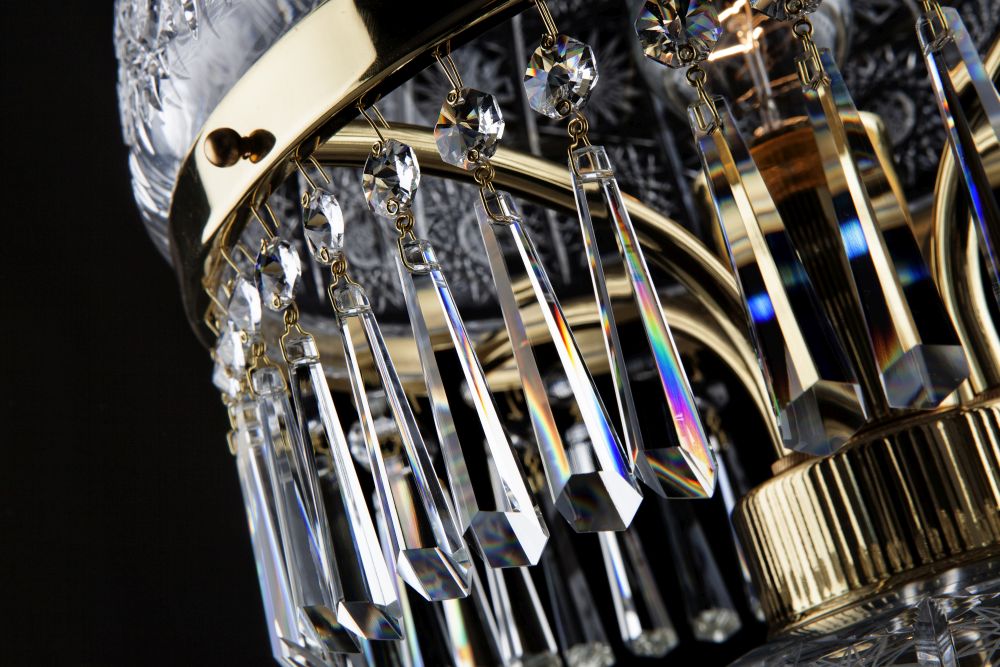 Détail des prismes en cristal aux reflets irisés suspendus aux bras dorés.