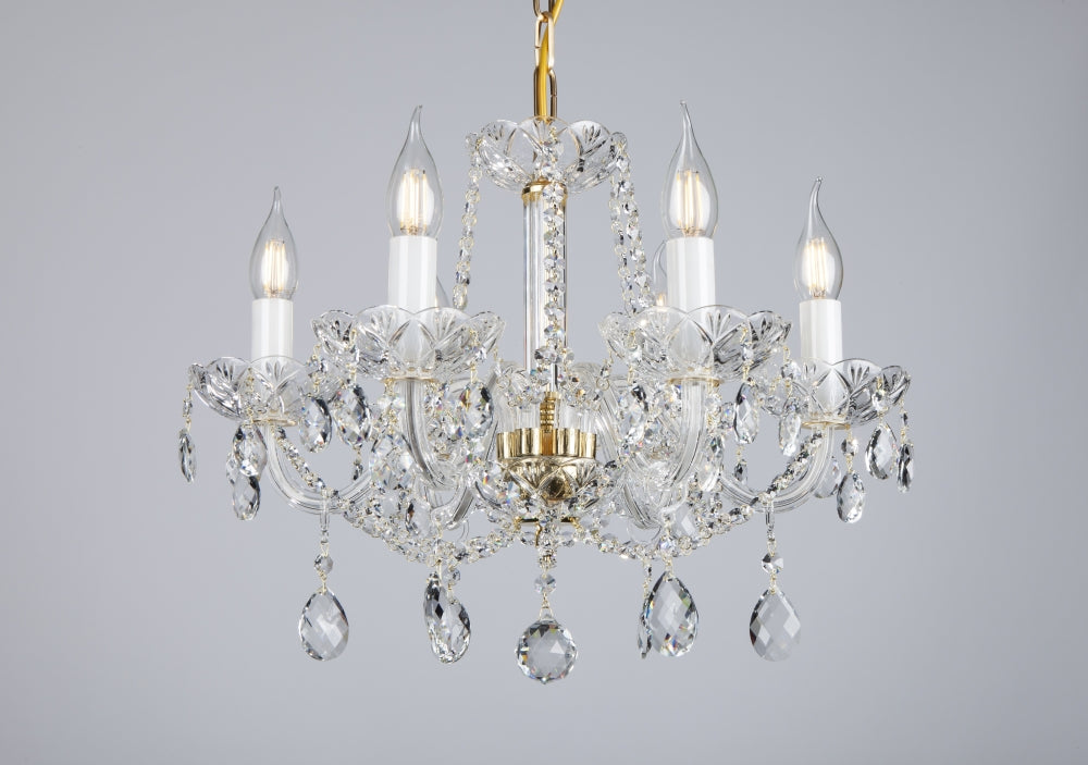 Lustre en cristal à cinq lumières, structure dorée et pampilles, présenté sur fond gris clair.
