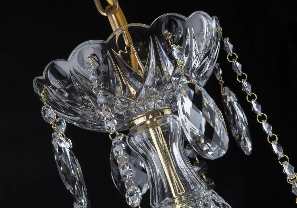Détail du sommet du lustre : cristal taillé en étoile, chaînettes dorées et pendeloques.