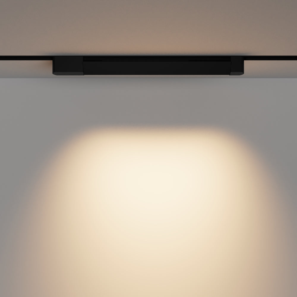 Face avant du spot noir sur rail fixé au plafond, halo lumineux diffusé