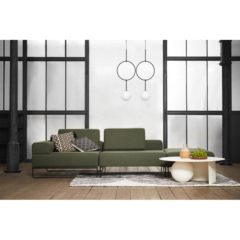 Mise en ambiance salon vert, suspension noire devant grande verrière industrielle