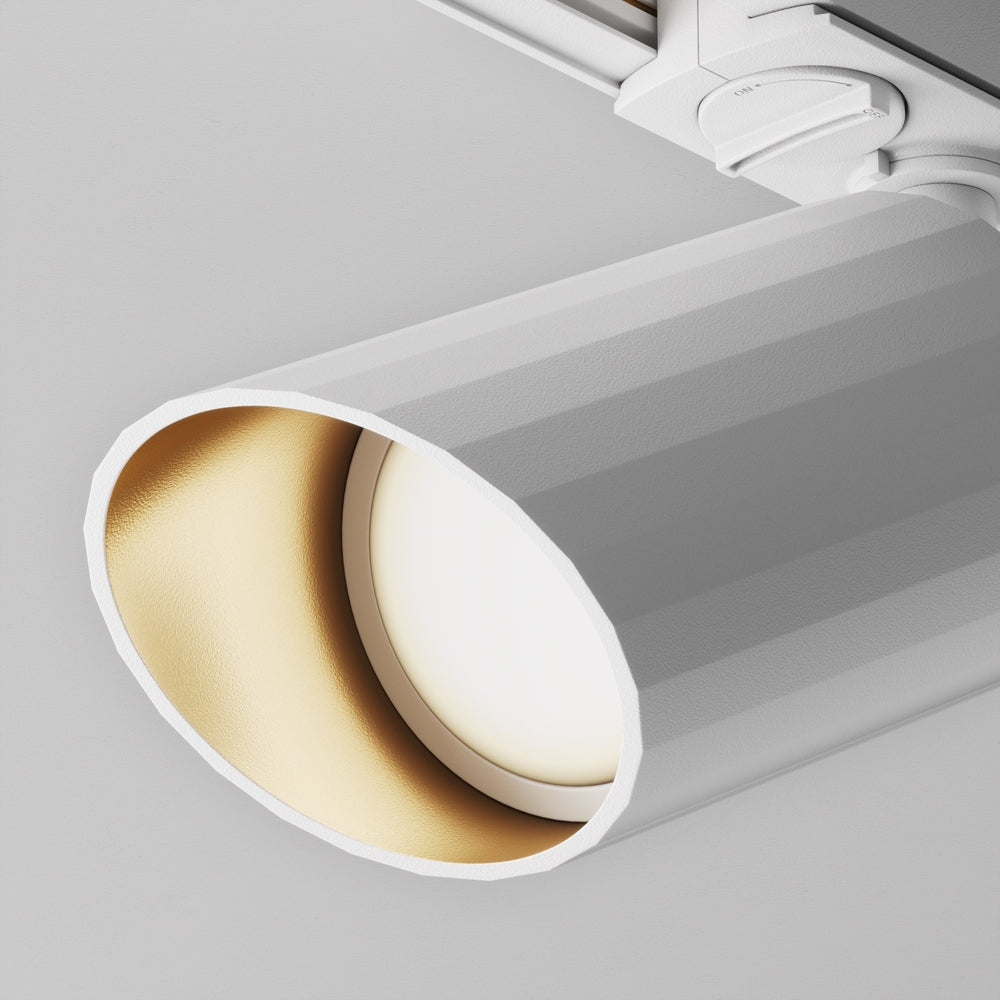 Gros plan sur l'intérieur doré du projecteur et son diffuseur blanc allumé.