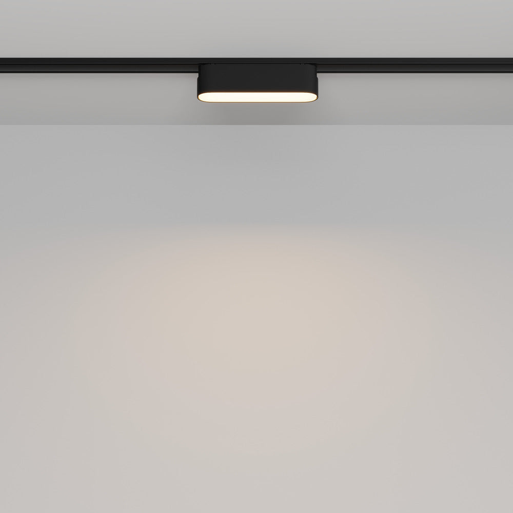 Vue de face du spot allumé sur rail, éclairant un mur blanc.