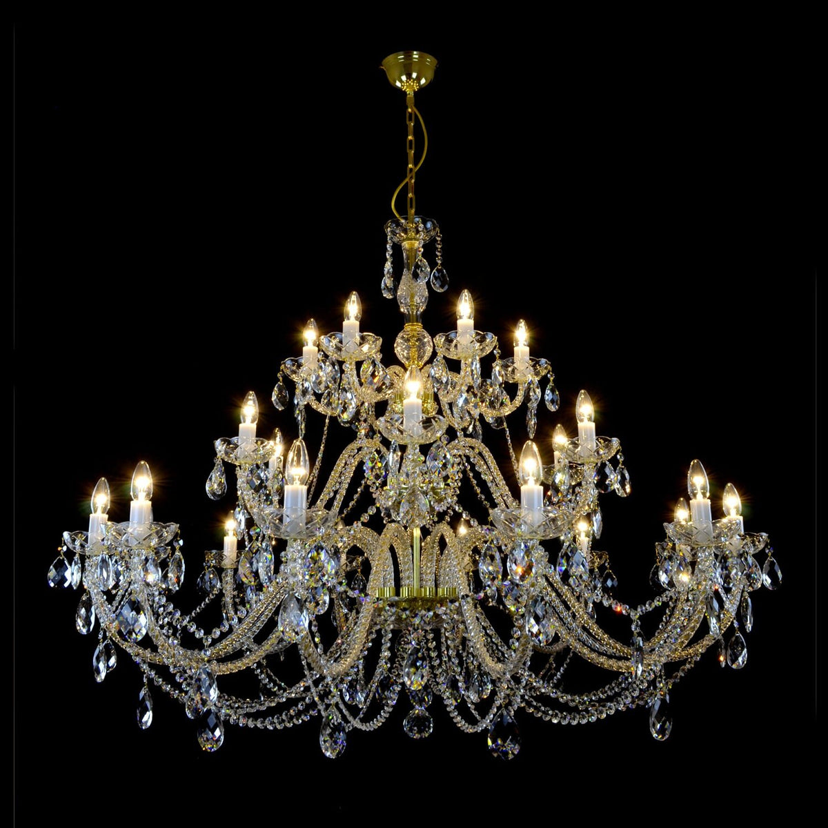 Lustre en cristal doré allumé, vue de face sur fond noir, nombreuses ampoules