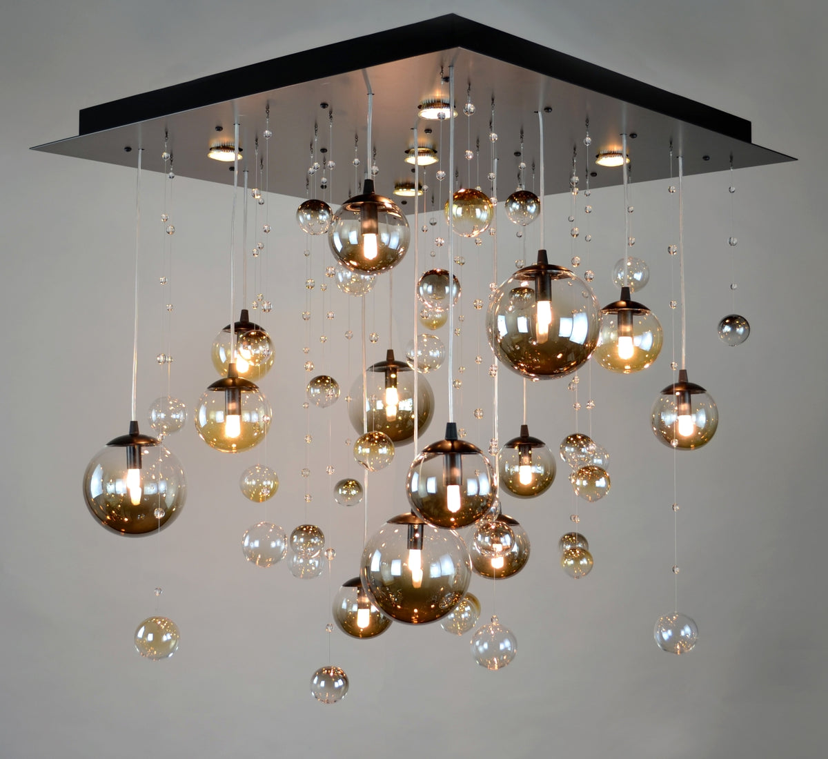 Plafonnier allumé montrant les boules de verre ambrées et claires diffusant une lumière chaude.