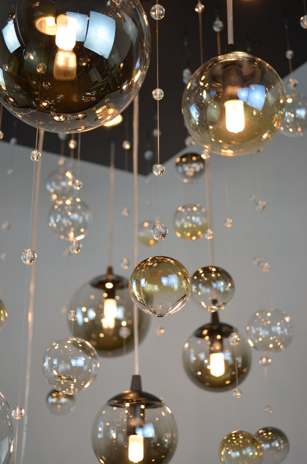 Vue en contre-plongée des suspensions et perles de cristal devant un plafond noir.