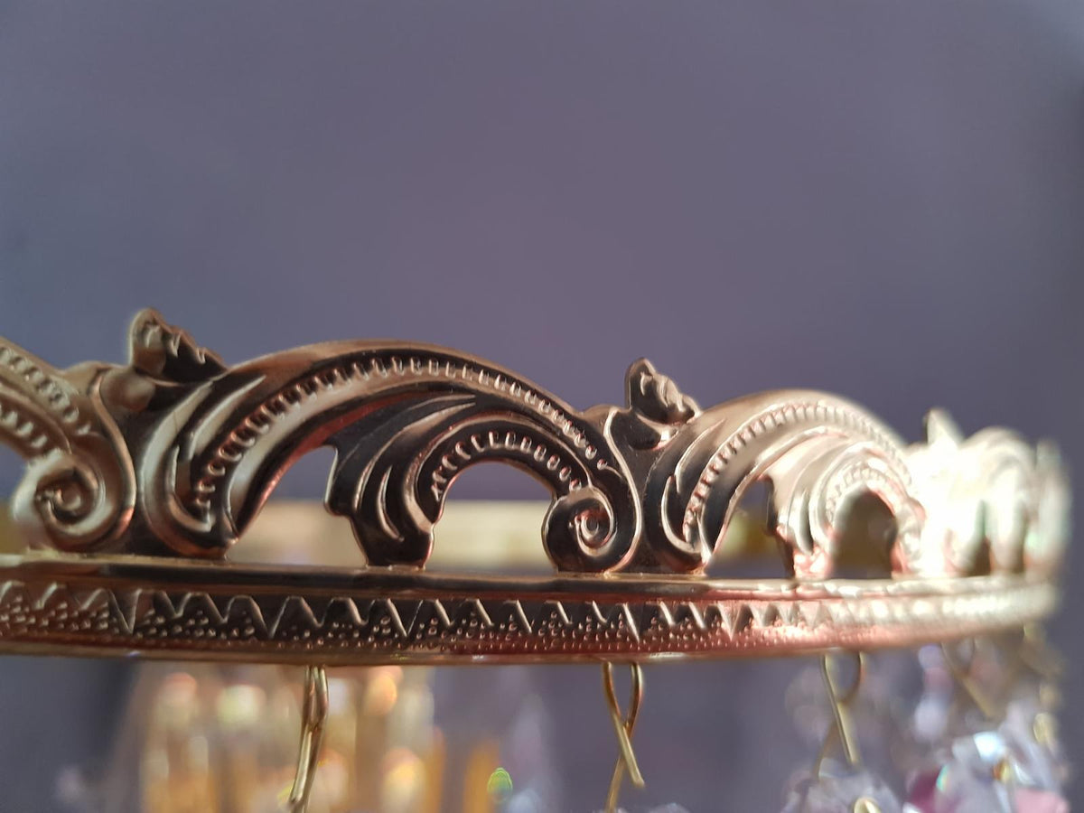 Gros plan du bandeau ajouré doré en forme de couronne à volutes