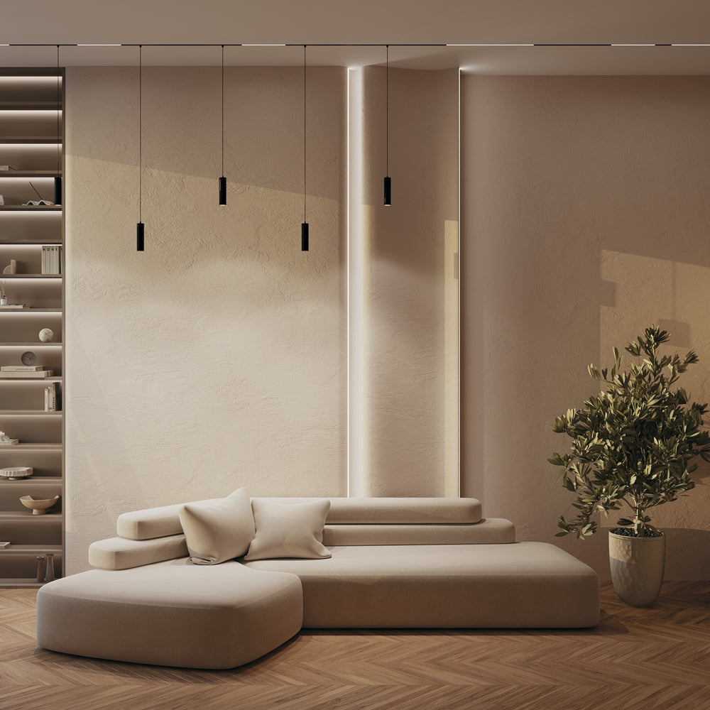Mise en ambiance : plusieurs suspensions noires sur rail éclairant un salon beige avec canapé.