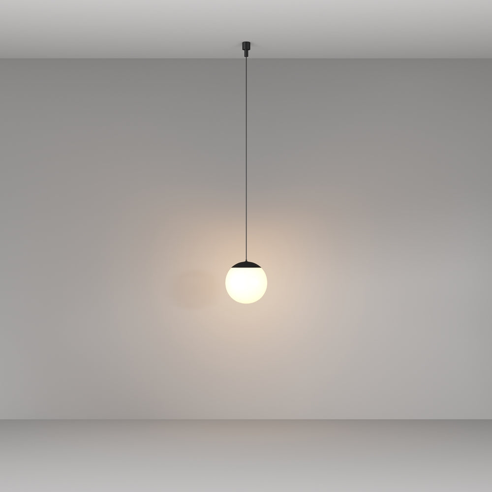 Vue de face du luminaire suspendu éclairé dans une pièce très sombre.