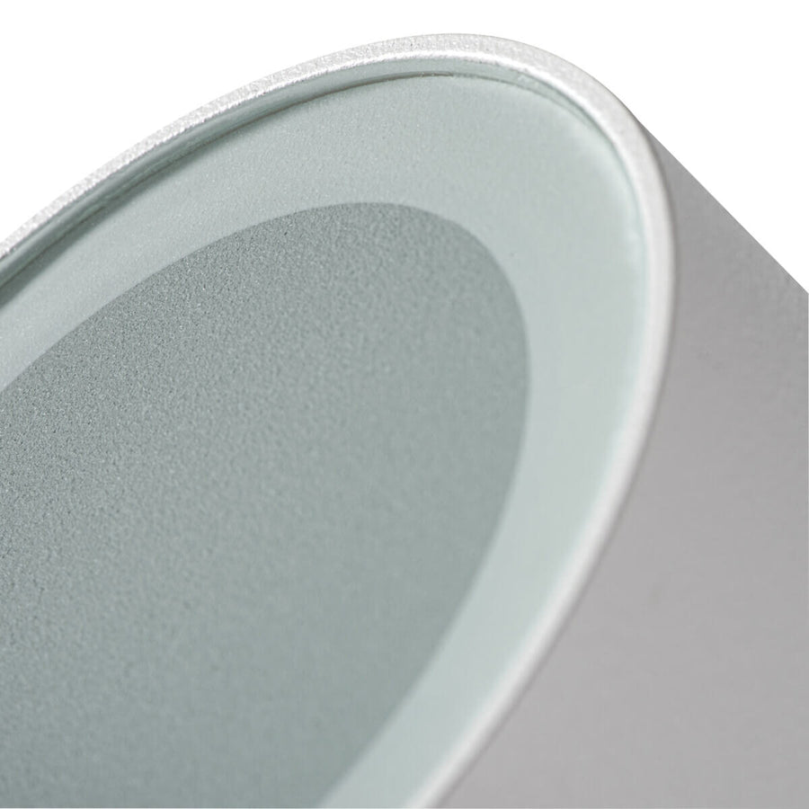 Détail rapproché du diffuseur gris et de la bague métallique du spot blanc.