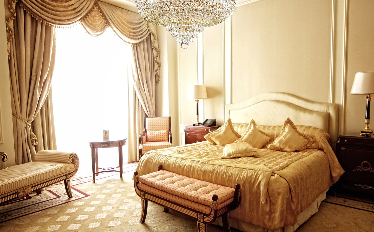 Lustre allumé au plafond d'une chambre dorée avec lit et rideaux