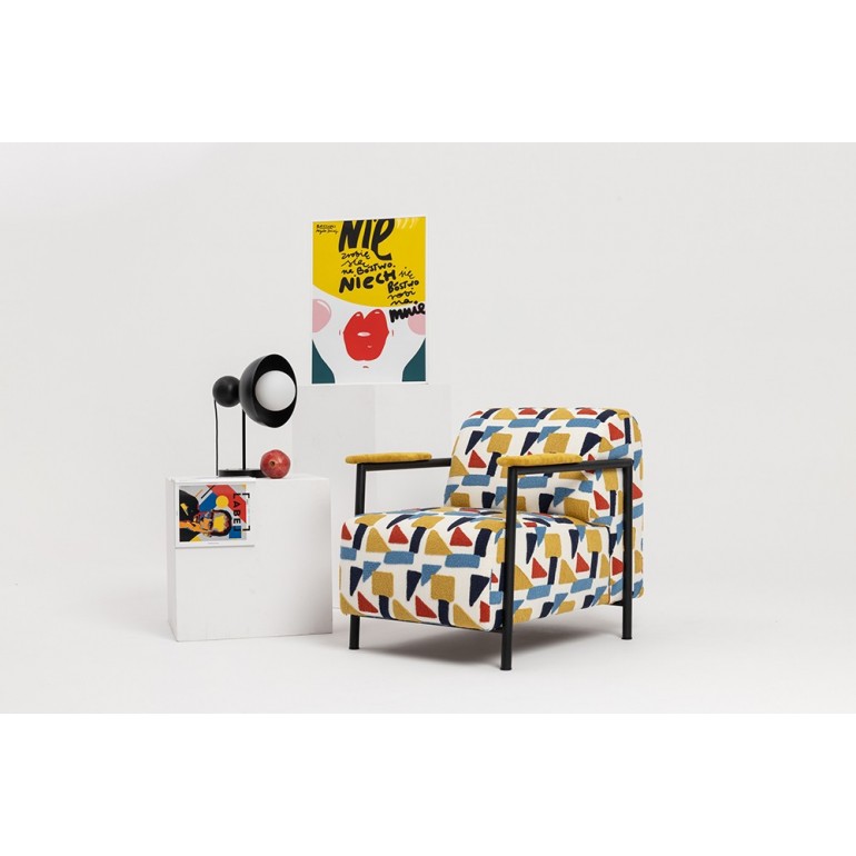 Mise en ambiance avec lampe noire posée sur un meuble blanc près d'un fauteuil.