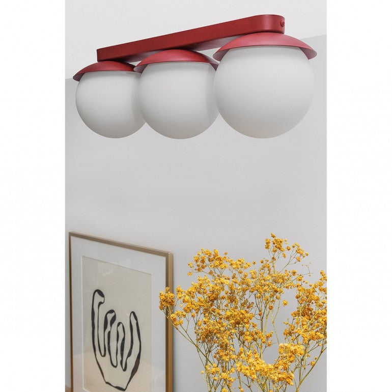 Mise en ambiance du plafonnier rouge fixé au plafond, cadre et fleurs jaunes en dessous