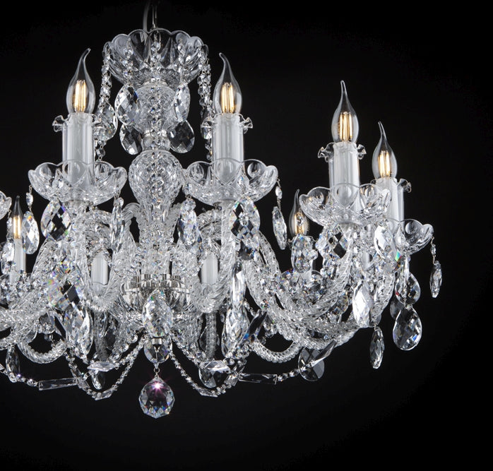 Vue rapprochée du lustre sur fond noir, détaillant les bras et pendentifs en cristal.