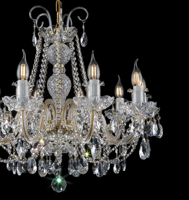 Vue de trois quarts du lustre, bras courbes en verre et cristaux taillés.