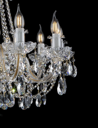 Détail rapproché des bras, coupelles ciselées et pendants de cristal facettés.