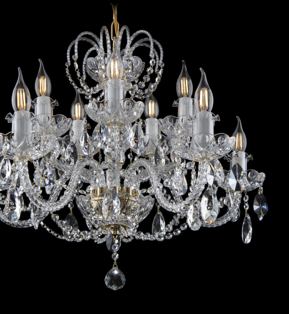 Gros plan sur les bras du lustre en cristal, bougies et chaînettes de pendentifs scintillants.