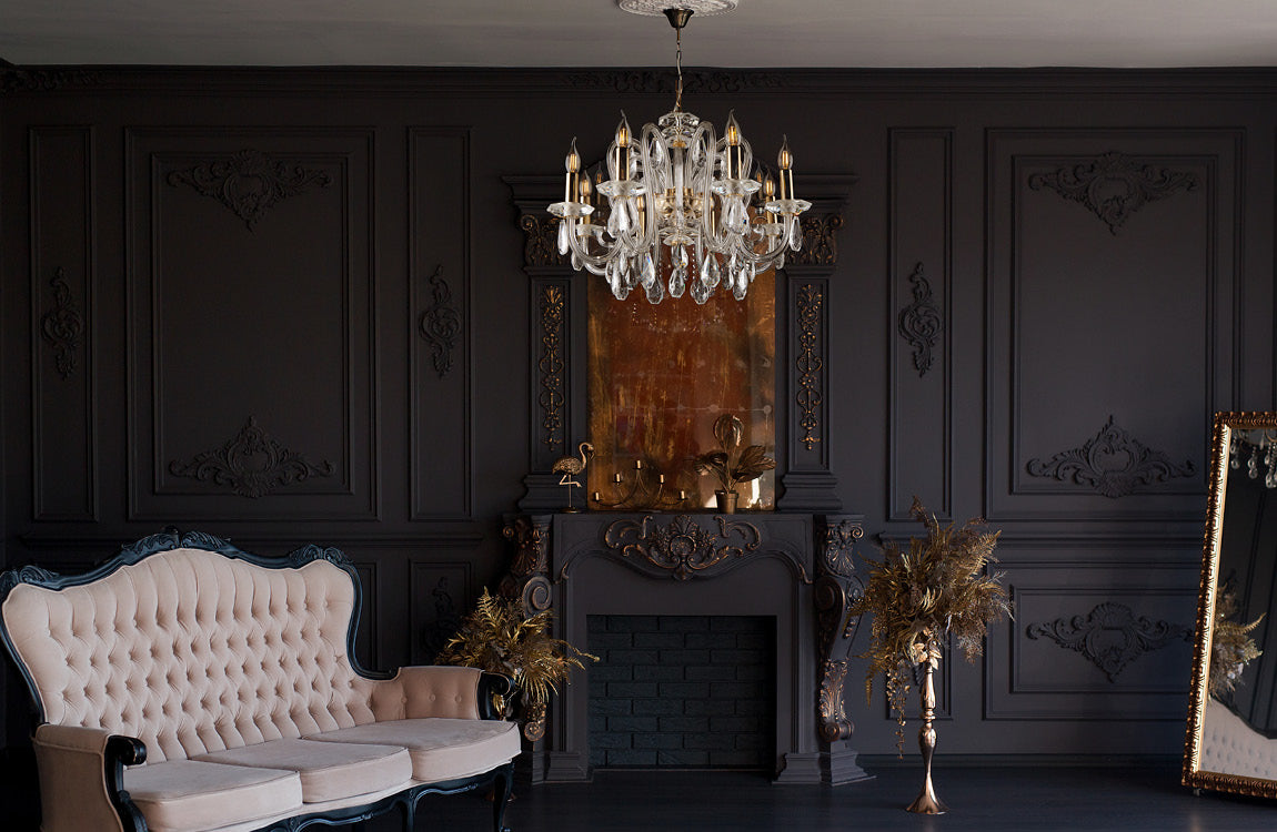 Lustre installé au centre d'un salon sombre avec canapé capitonné et miroir doré