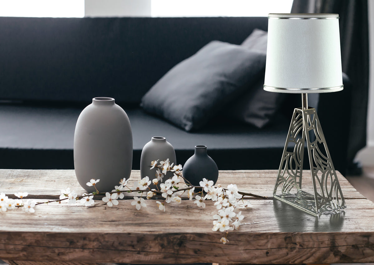 Mise en ambiance sur table en bois avec vases gris et branches fleuries.