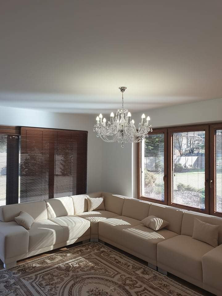 Lustre allumé suspendu au plafond d'un salon avec canapé d'angle beige