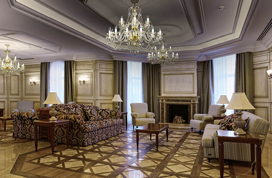 Mise en ambiance du lustre suspendu dans un grand salon classique au plafond mouluré