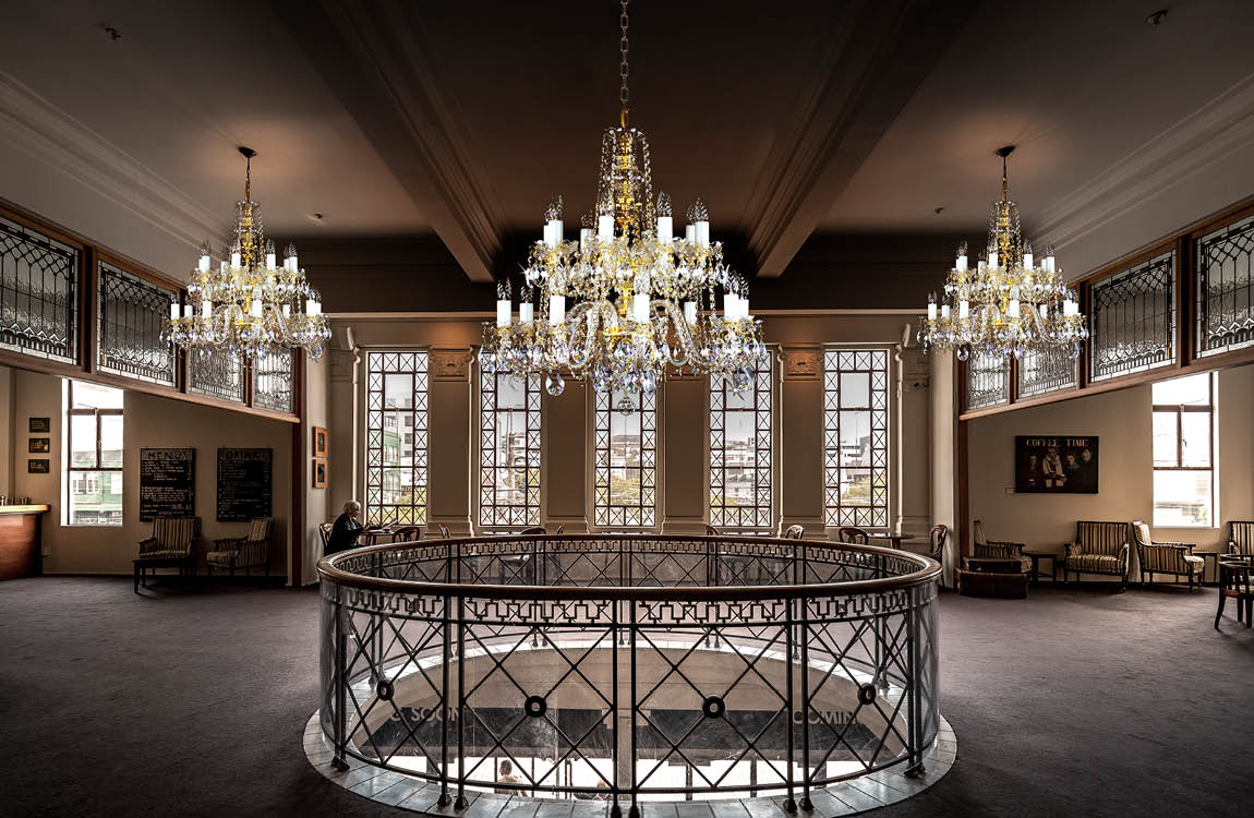 Mise en ambiance, trois lustres suspendus dans un grand hall au plafond mouluré